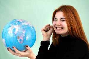 woman looking at globe and thinking about which new language she would like to learn