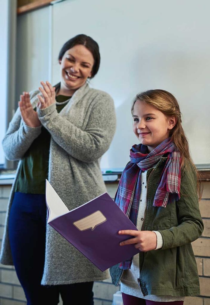 teacher and school child reading from school book